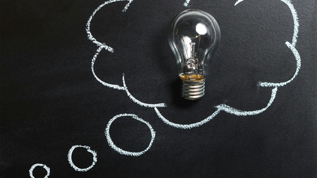 A bubble speech drawn on a blackboard, with a light bulb in the center