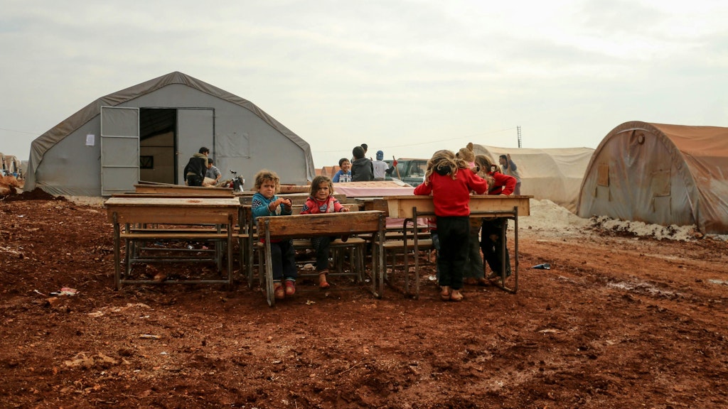 Children sitting at their desks outside at a refugee campsite