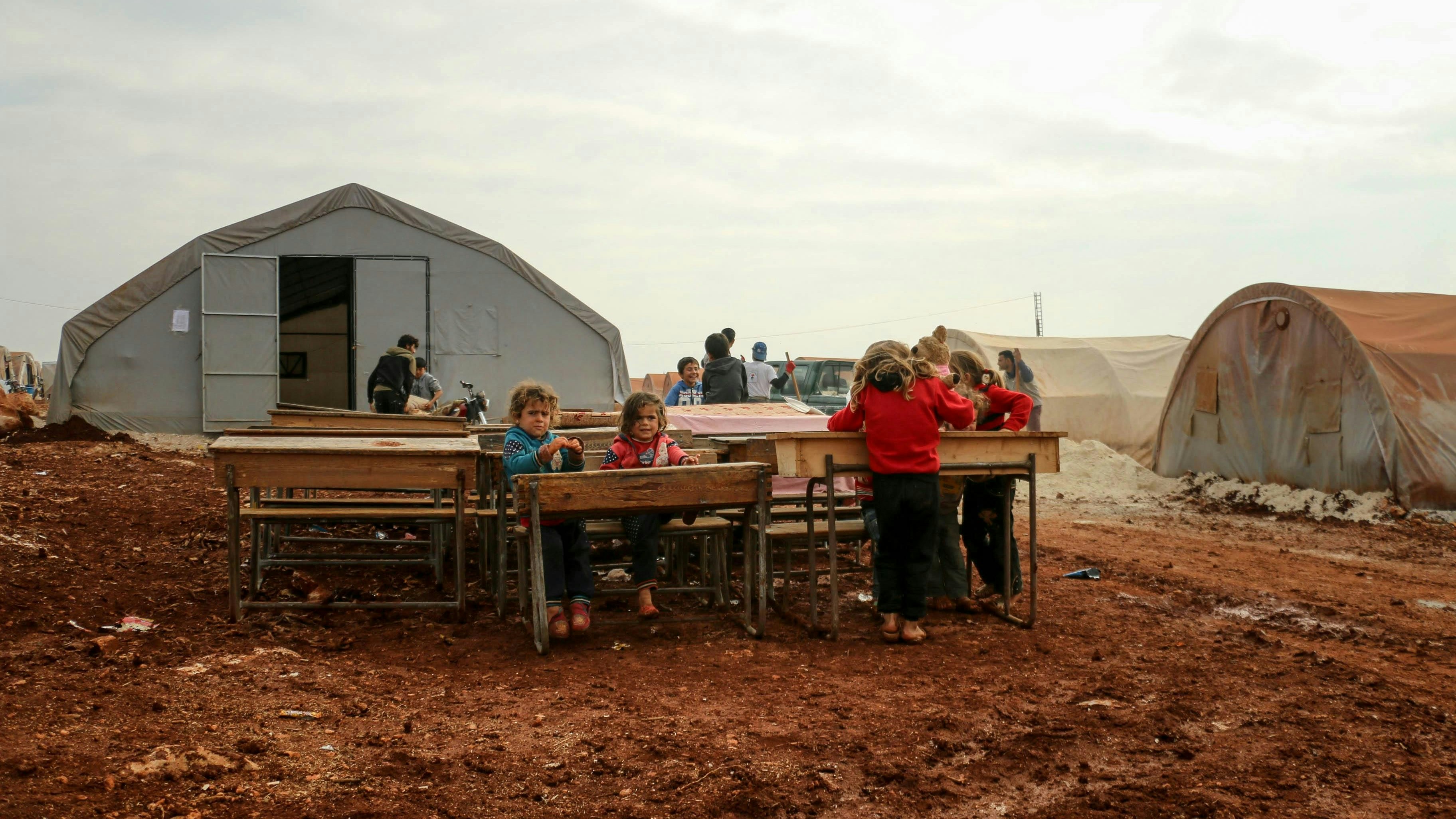 Children sitting at their desks outside at a refugee campsite