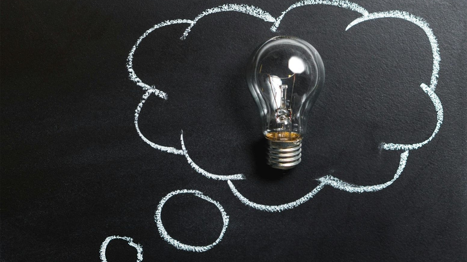 A bubble speech drawn on a blackboard, with a light bulb in the center