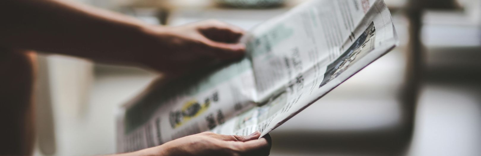 Hands holding an open newspaper